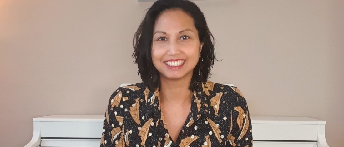 Nurjanah Bruggeman glimlachend aan de piano